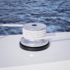 Stainless steel boat winch with white rope on a yacht deck.