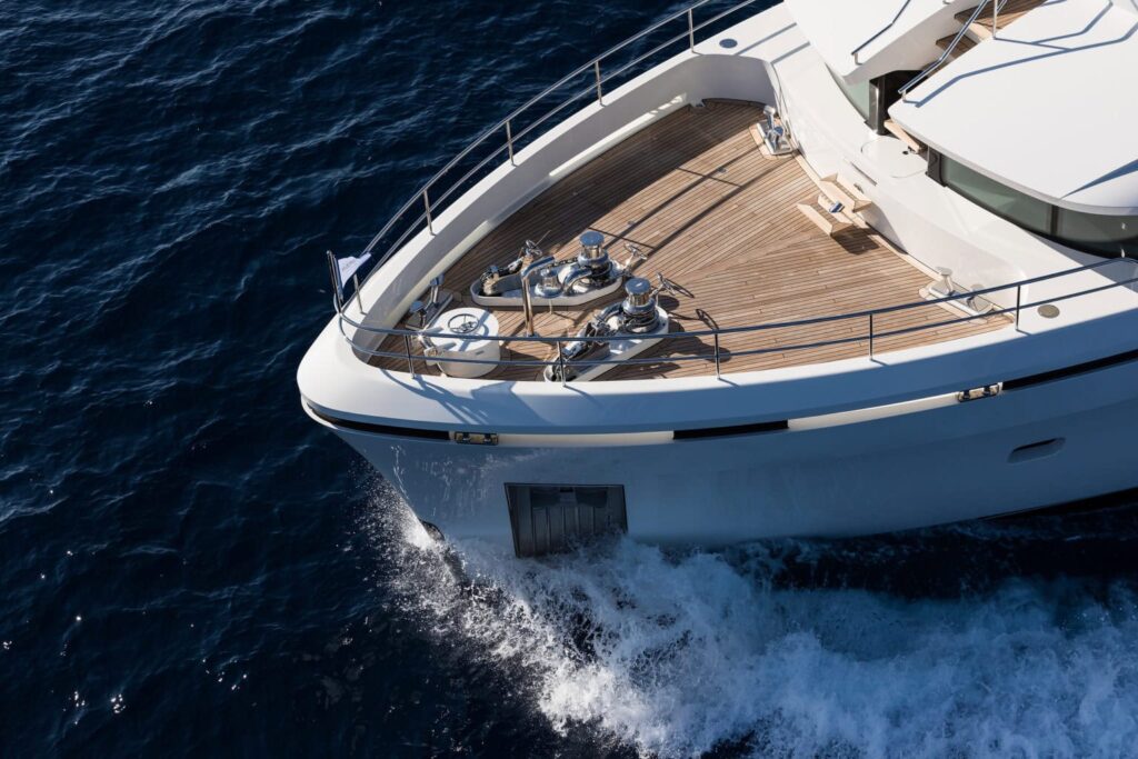 Luxury yacht deck with polished winches and safety railings on the ocean.