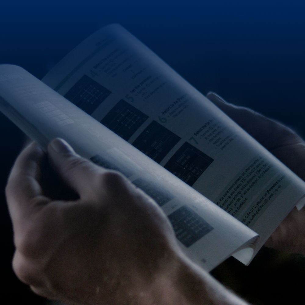 A person's hands holding open a Muir anchoring system operation guide or manual.