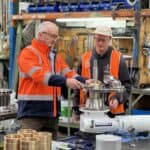 Two Muir technicians in a workshop assembling a Mega stainless steel vertical windlass.